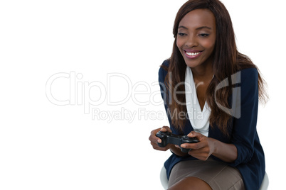 Smiling businesswoman playing video game while sitting on stool