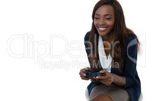 Smiling businesswoman playing video game while sitting on stool