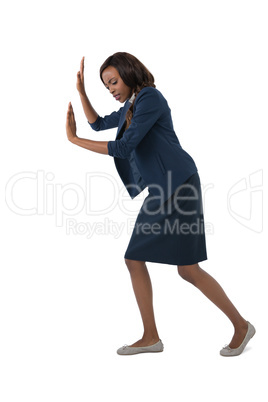 Full length of businesswoman pushing something on white background