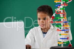 Smiling schoolboy experimenting molecule model in laboratory