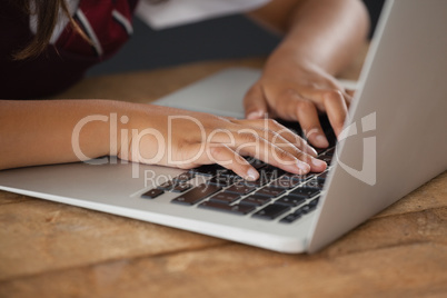 Schoolgirl using laptop against blackboard in classroom