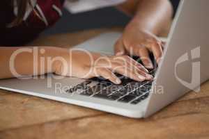 Schoolgirl using laptop against blackboard in classroom