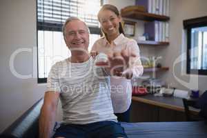 Portrait of smiling female doctor and senior male patient with arms raised