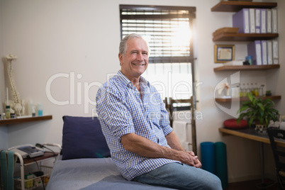 Portrait of smiling senior male patient sitting on bed