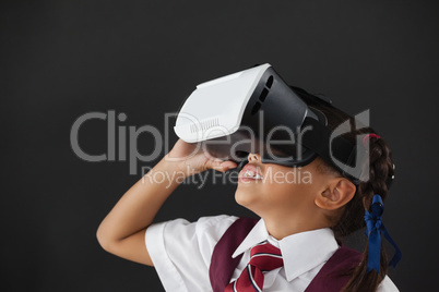 Schoolgirl using virtual reality headset against blackboard