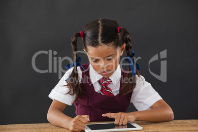 Schoolgirl using digital tablet against blackboard