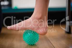 Low section of boy stepping on stress ball