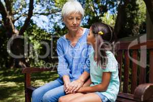 Grandmother and granddaughter holding hands while sitting on bench