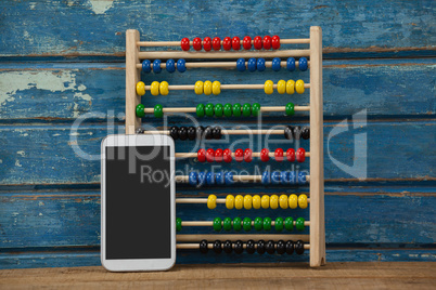 Abbacus game and smartphone against wooden background