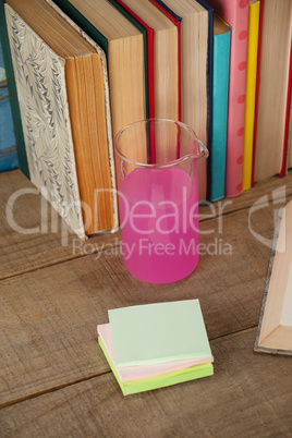 Stack of books, chemical beaker and sticky notes