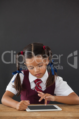 Schoolgirl using digital tablet against blackboard