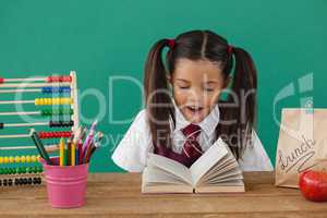 Schoolgirl reading a book against green background