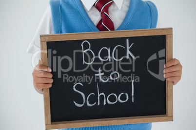 Schoolboy holding writing slate with text back to school against white background