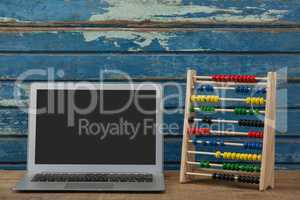 Abbacus game and laptop against wooden background