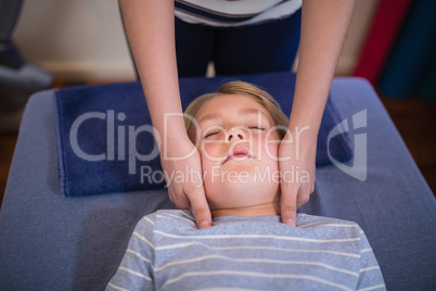 High angle view of boy receiving neck massage from female therapist