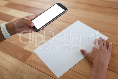 Woman holding a document and using mobile phone