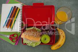 School supplies and lunch box arranged on chalkboard