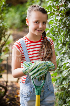 Portrait of smiling girl standing with gardening fork
