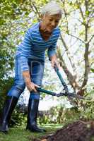 Low angle view of smiling senior woman using hedge trimmers