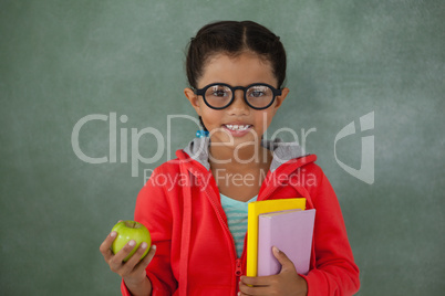 Young girl in glasses holding apple and books