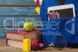 School supplies, apple, digital tablet and magnifying glass on wooden table