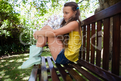 Side view of thoughtful girl sitting on wooden bench