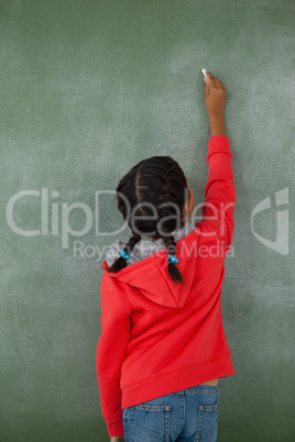 Young girl writing on chalk board