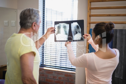 Rear view of senior male patient and female therapist looking at x-ray