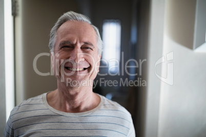 Close-up portrait of smiling senior male patient standing in corridor