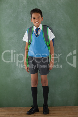 Schoolboy standing in front of chalkboard in classroom