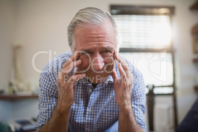 Low angle portrait of senior male patient frowning with headache