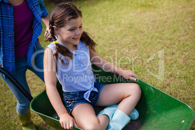 High angle view of mother pushing smiling daughter in wheelbarrow