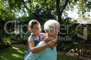 Smiling woman carrying granddaughter with flowers