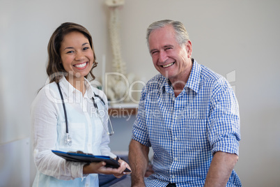 Portrait of smiling senior male patient and female therapist holding file
