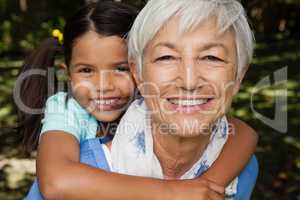 Close-up portrait of smiling grandmother giving piggyback to granddaughter