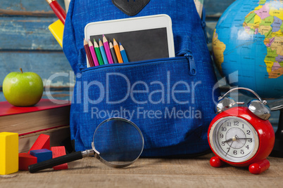 School supplies, apple, globe, digital tablet and magnifying glass on wooden table