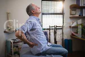 Side view of senior male patient suffering from back ache while looking up on bed