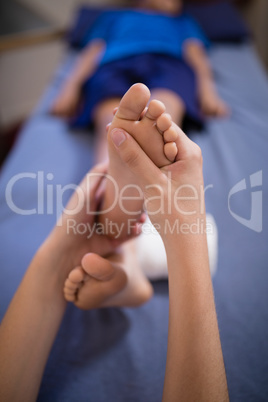 High angle view of boy receiving foot massage from female therapist while lying on bed