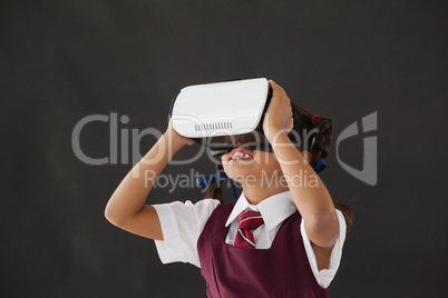 Schoolgirl using virtual reality headset against blackboard