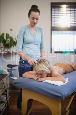 Female therapist using ultrasound machine over boy lying on bed