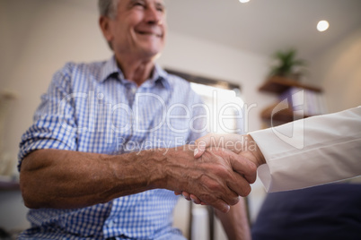 Senior male patient shaking hands with female therapist