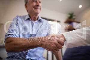 Senior male patient shaking hands with female therapist