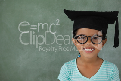 Young girl with graduation hat against chalk board