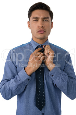 Portrait of businessman adjusting necktie