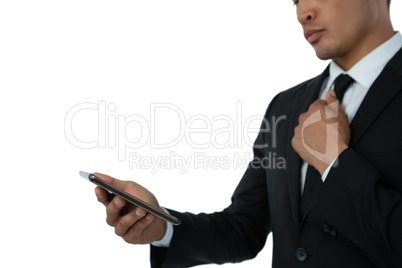 Mid section of businessman holding tie while using mobile phone