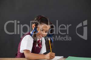 Schoolgirl doing her homework against chalkboard