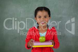 Young girl holding apple and books