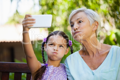 Girl and grandmother making faces while taking selfie