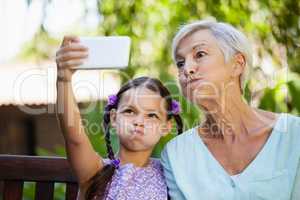 Girl and grandmother making faces while taking selfie