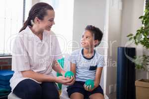 Smiling female therapist looking at boy holding stress balls